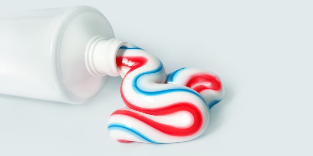 A woman cleaning her teeth with a toothbrush and toothpaste