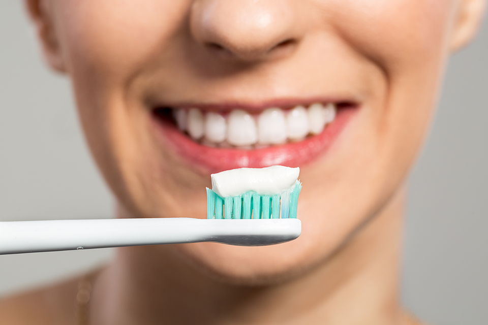 A woman cleaning her teeth with a toothbrush and toothpaste