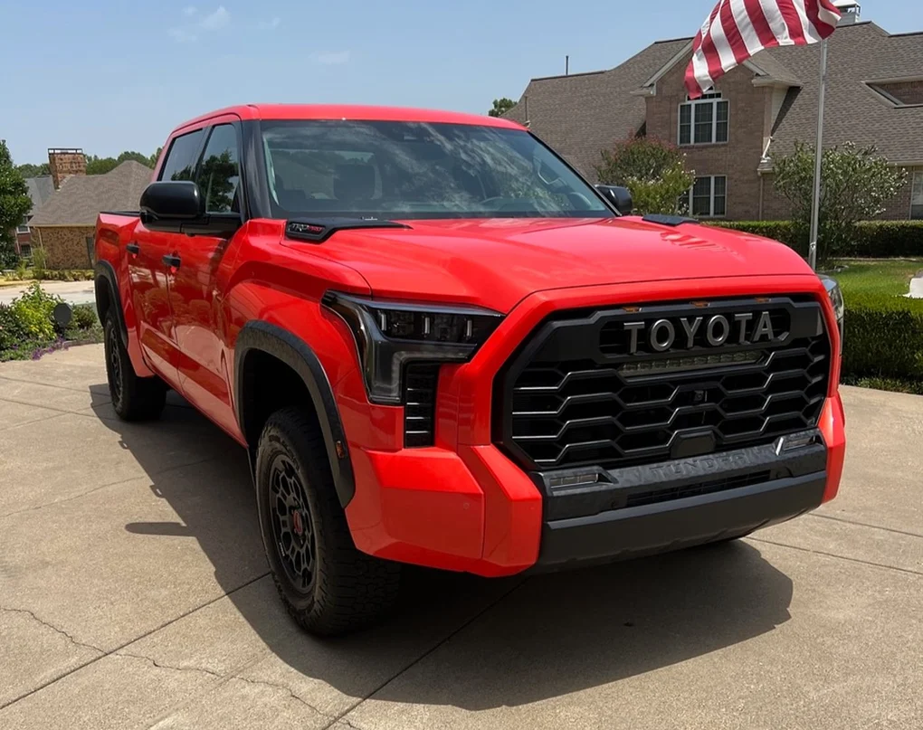 a red truck parked in a driveway, Toyota Tundra 2024